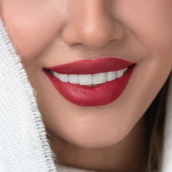 Close-up of a smiling woman with vibrant red lips and perfect teeth.